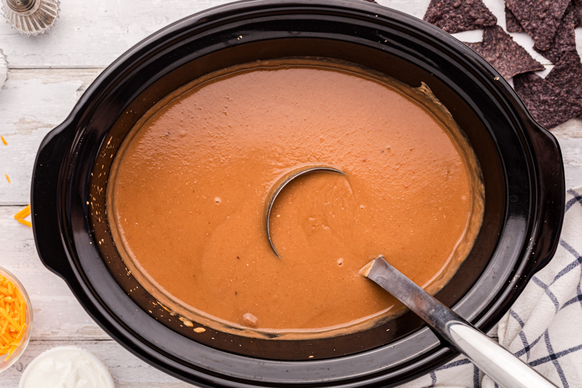 close-up overhead of slow cooker refried bean soup in a crockpot.