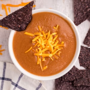 overhead of serving of slow cooker refried bean soup with cheese on top.