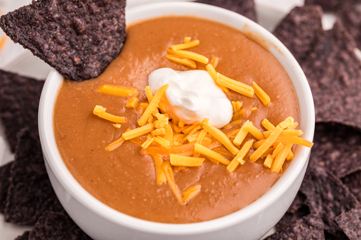 close-up serving of slow cooker refried bean soup in a bowl.