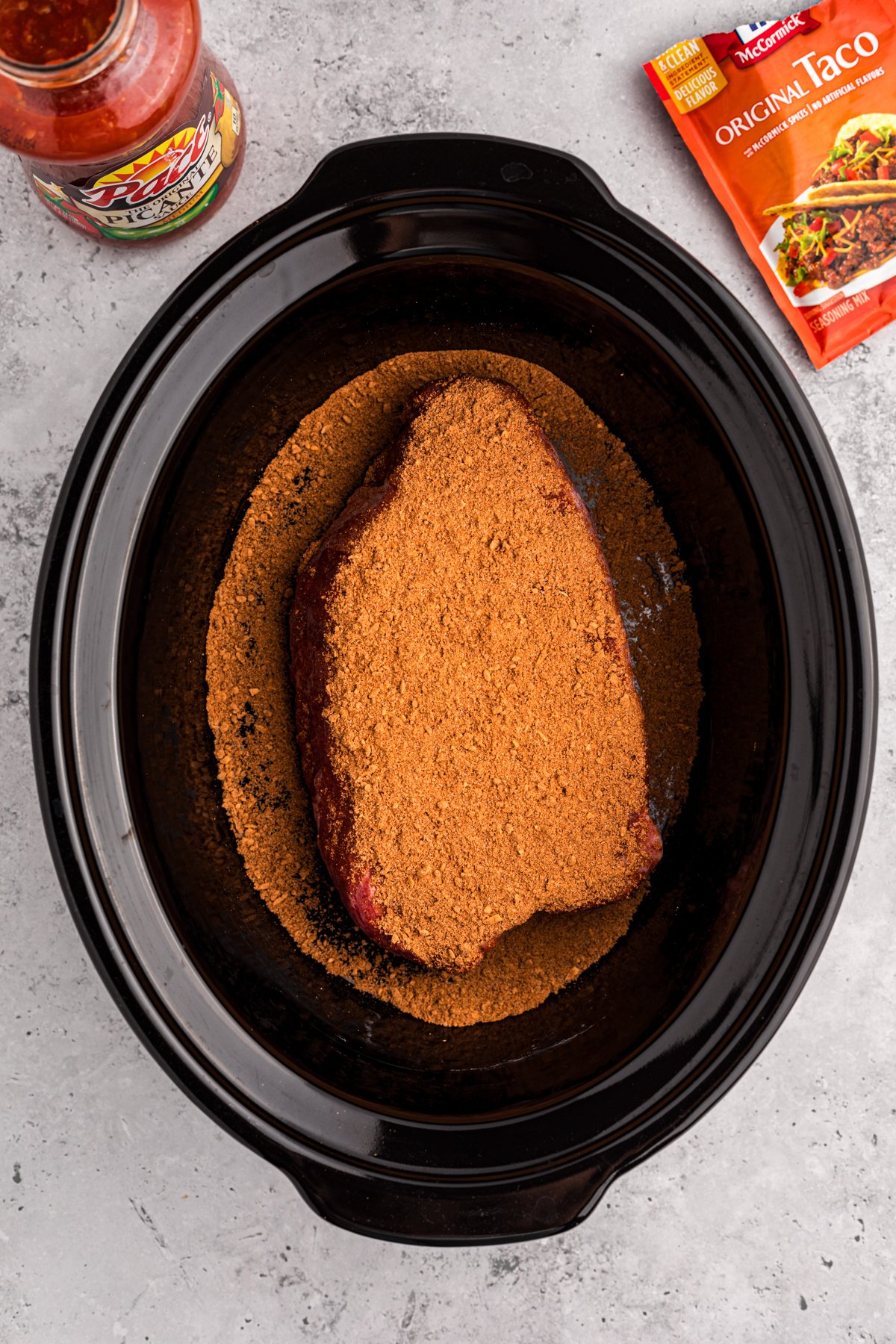 Chuck roast added to a crockpot with taco seasoning on top.