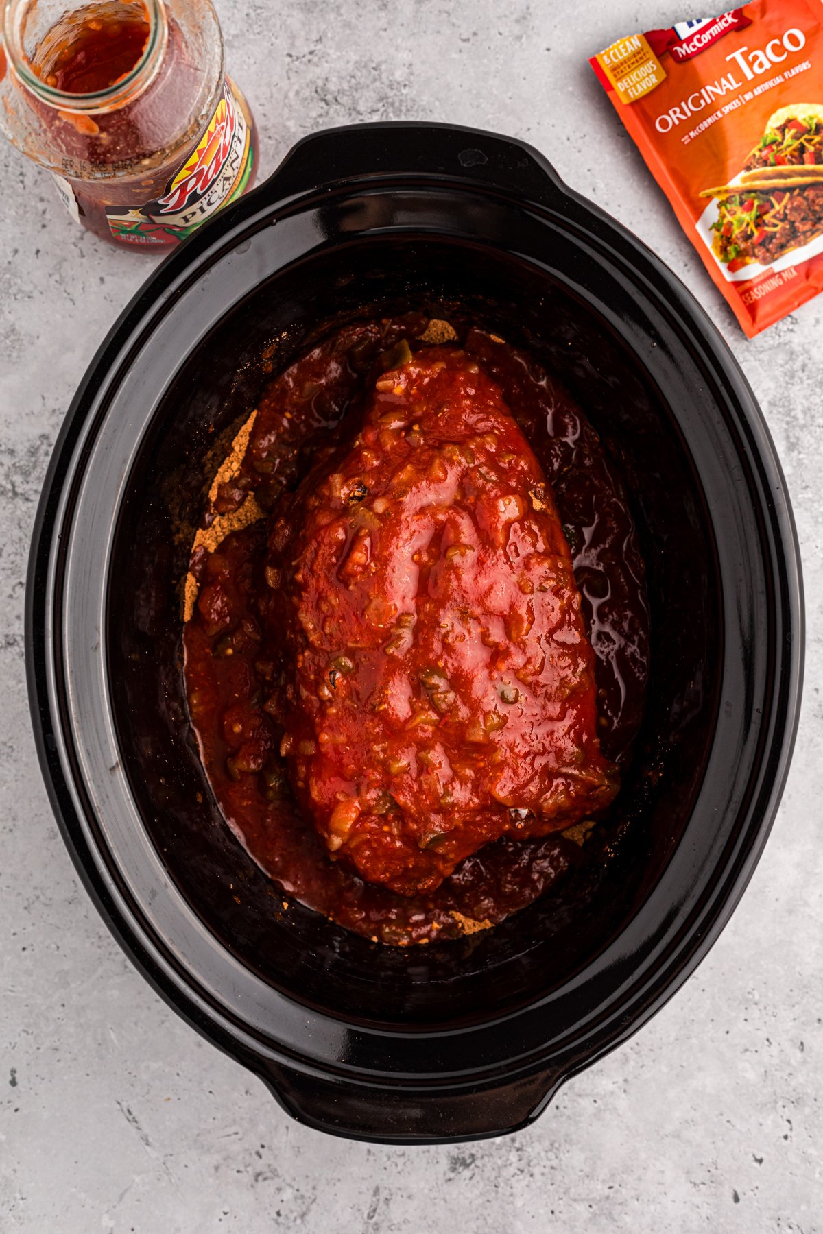Chuck roast with taco seasoning and salsa on top in a crockpot.