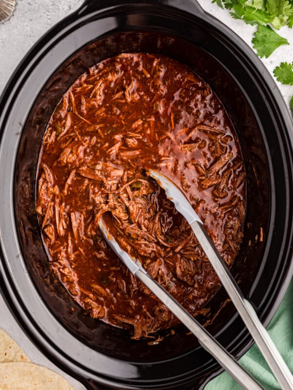 Slow cooker salsa beef with tongs ready to take some.