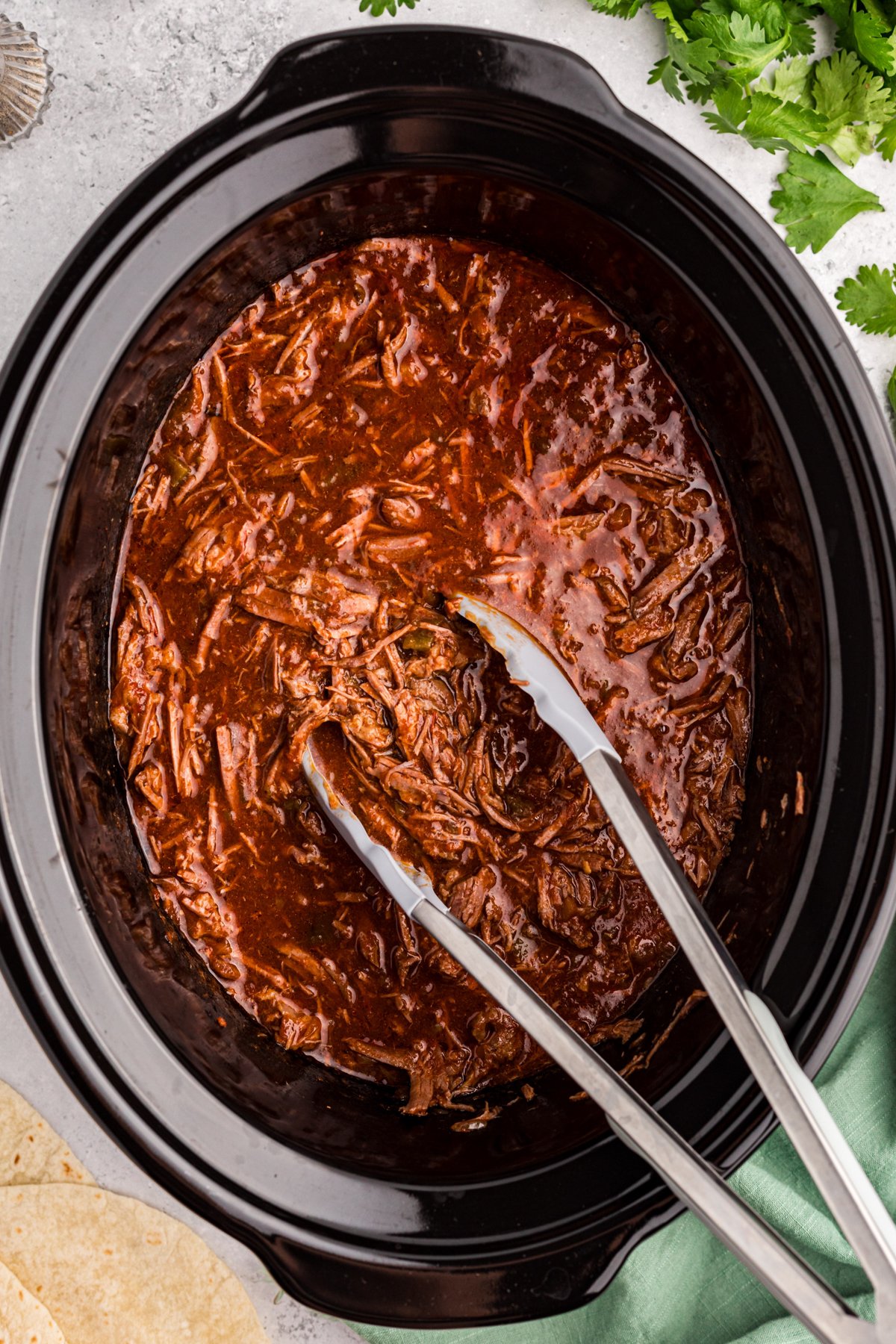 Slow cooker salsa beef with tongs ready to take some.