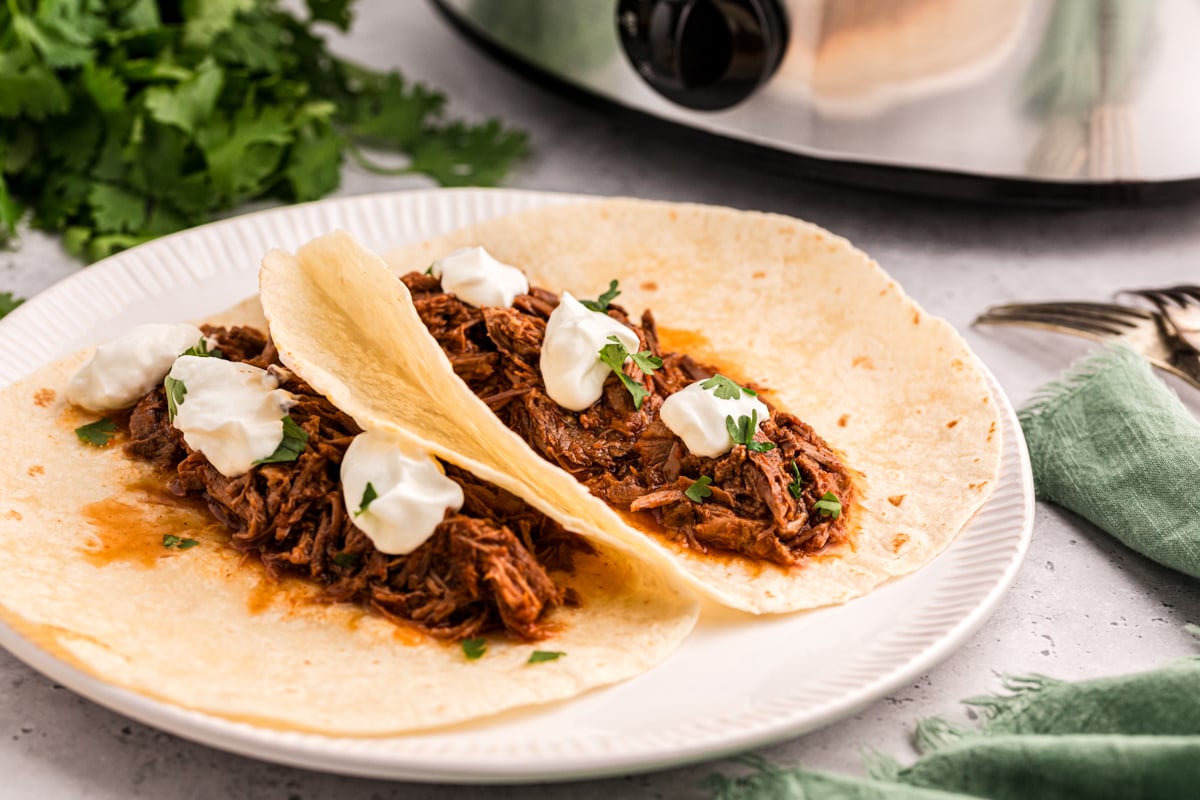 Two slow cooker salsa beef tacos on a plate.