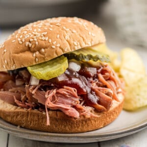 close-up of a slow cooker pulled ham sandwich with toppings on a plate.