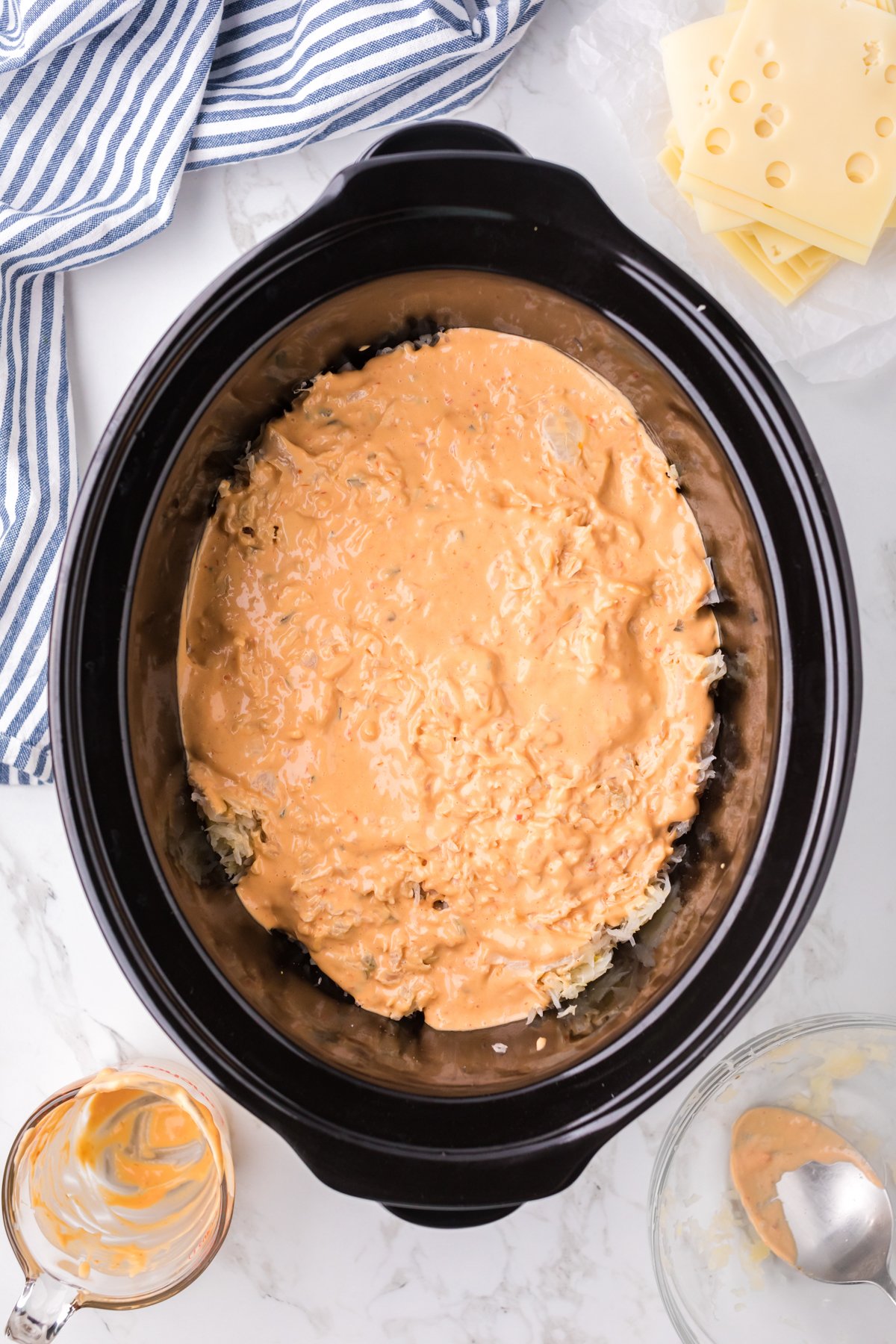 Thousand island dressing on top of chicken and sauerkraut in a crockpot.