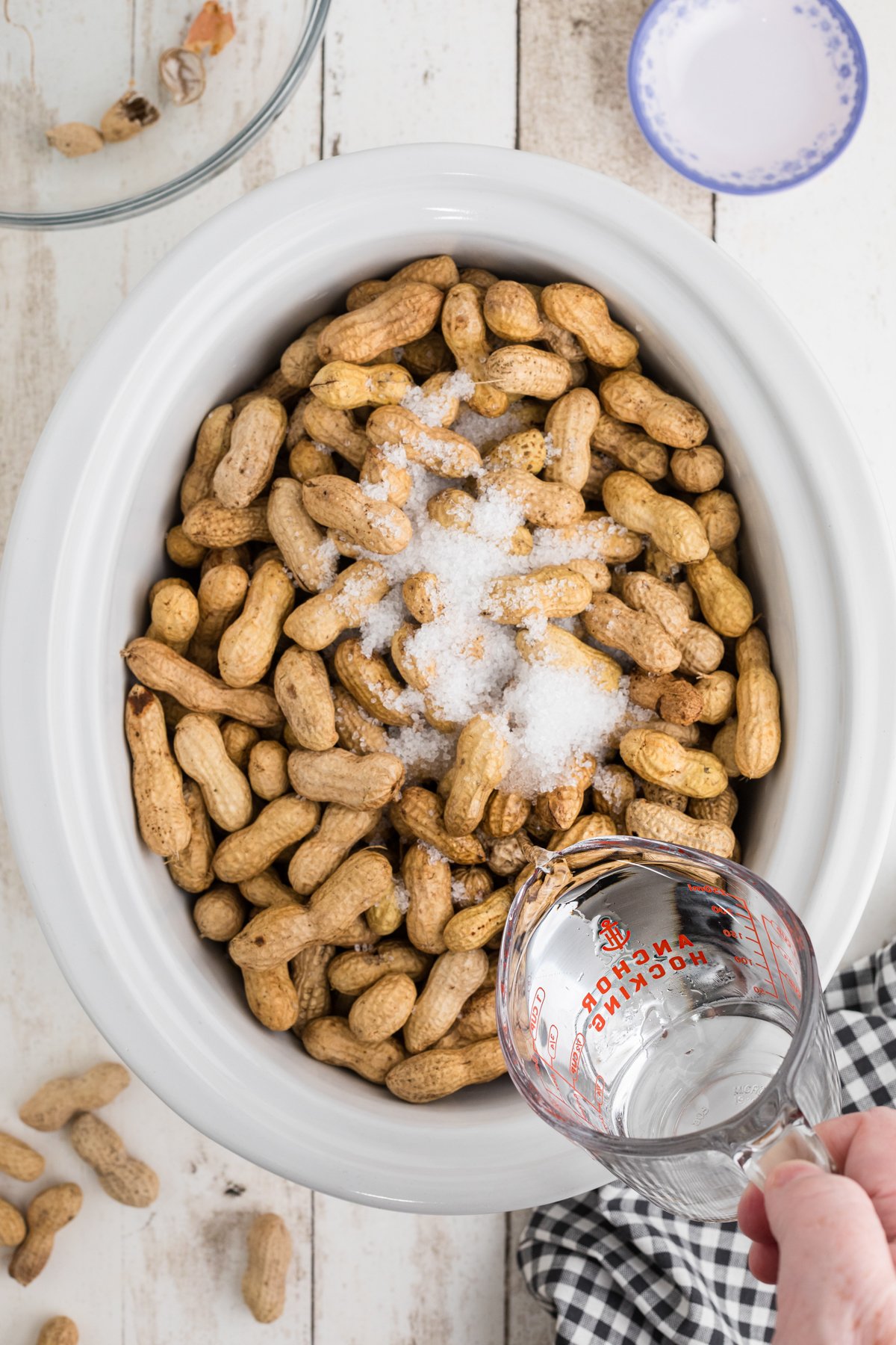 Pouring water into a slow cooker with peanuts and salt.