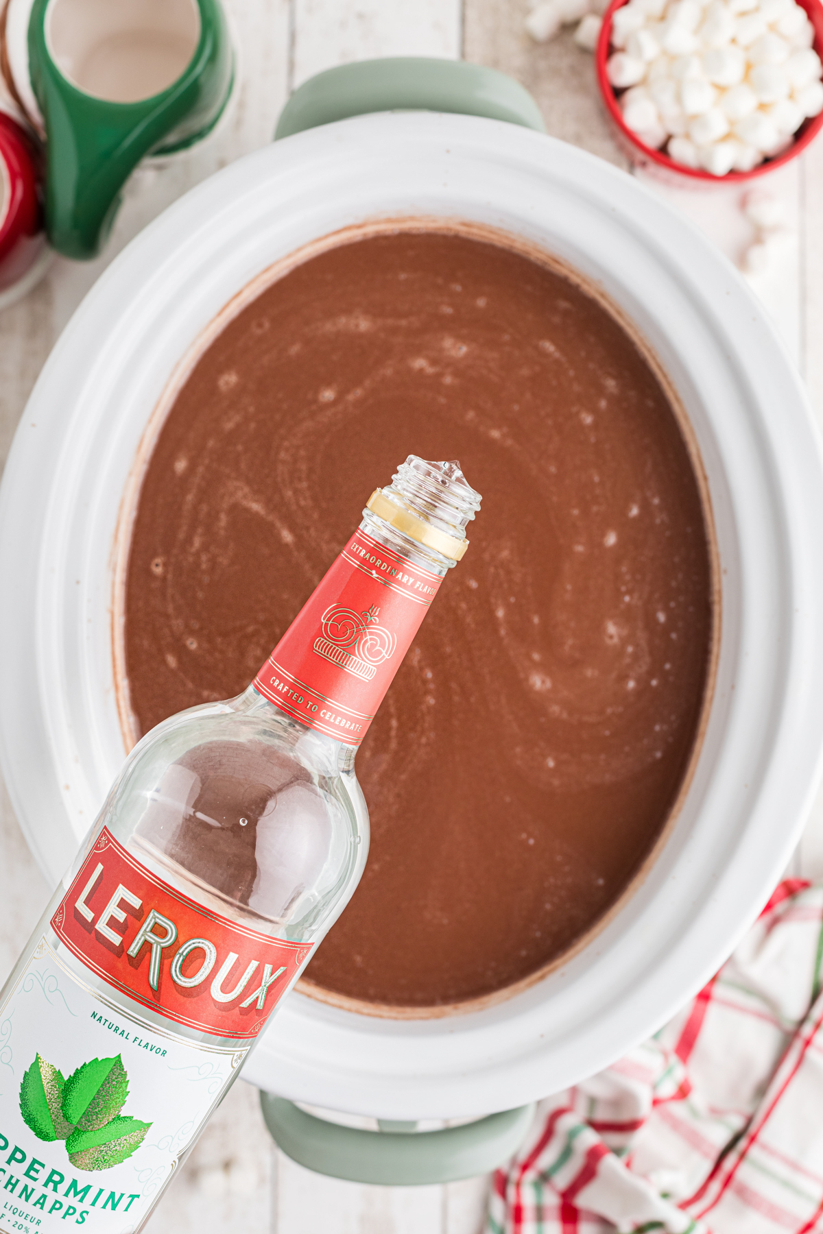 Adding peppermint schnapps to boozy hot chocolate in a crockpot.