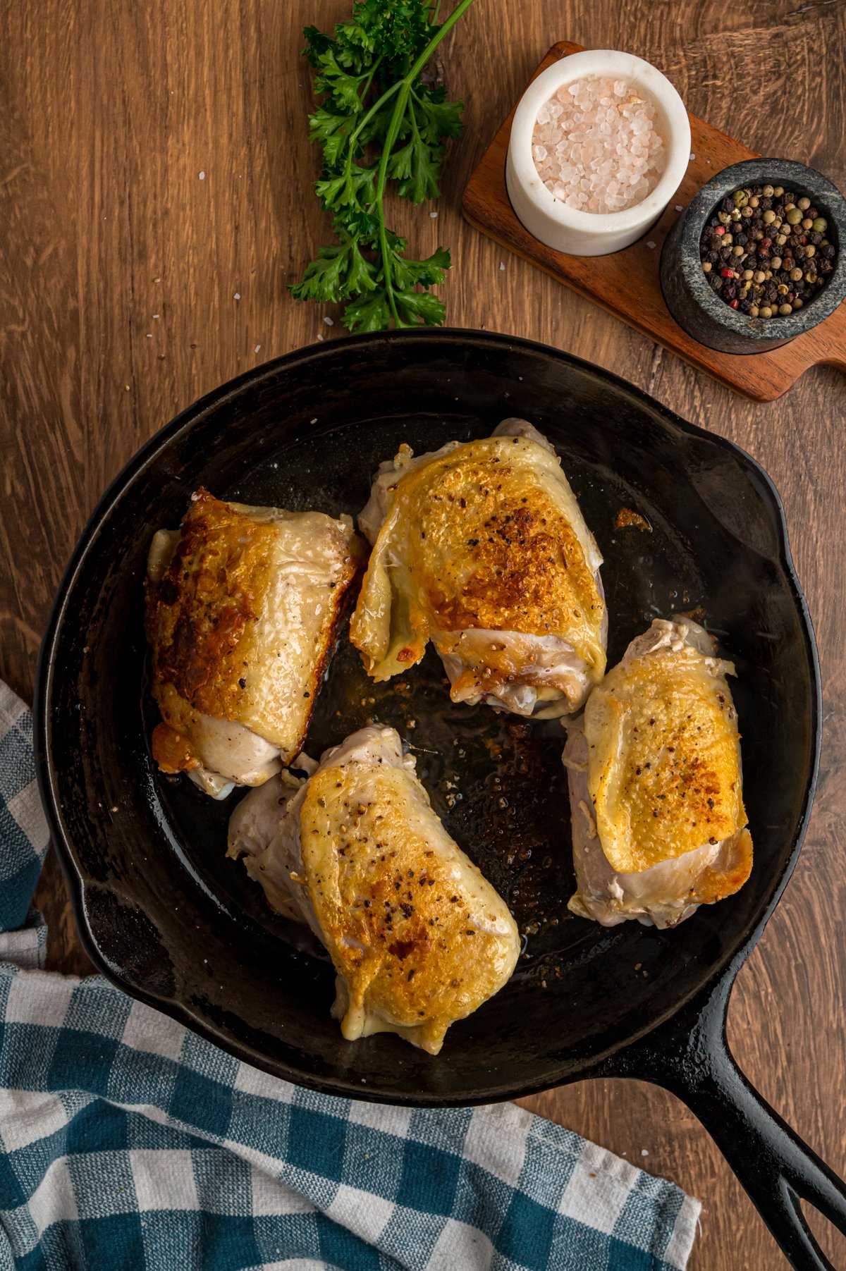 Chicken thighs searing in a cast iron skillet.