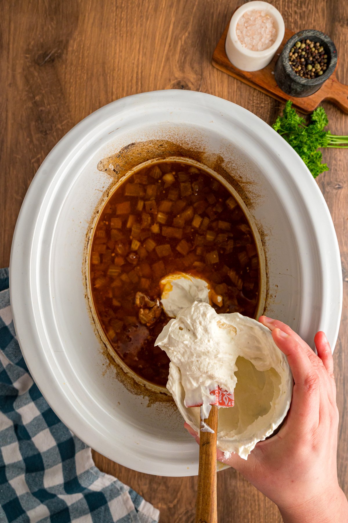 A combination of sour cream and flour being added to a crockpot.