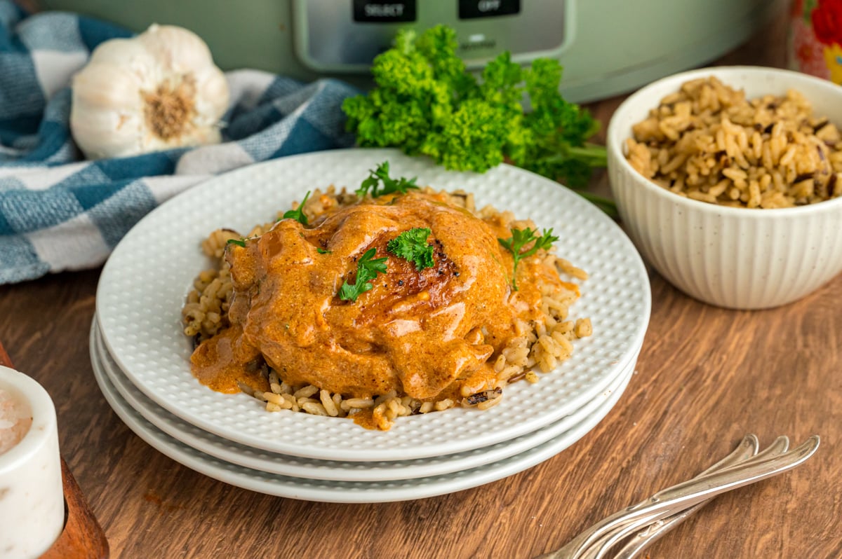 Serving of slow cooker chicken paprika on a bed of rice with sauce on top. 