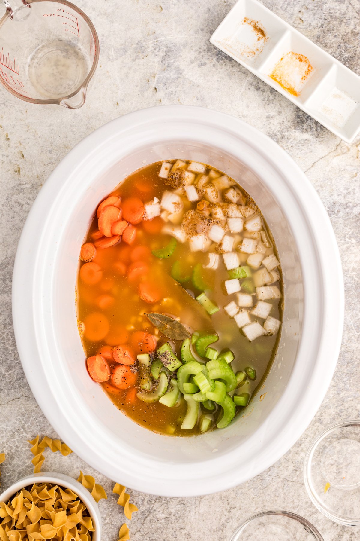 Chicken broth added to a crockpot with chicken, veggies, and spices.