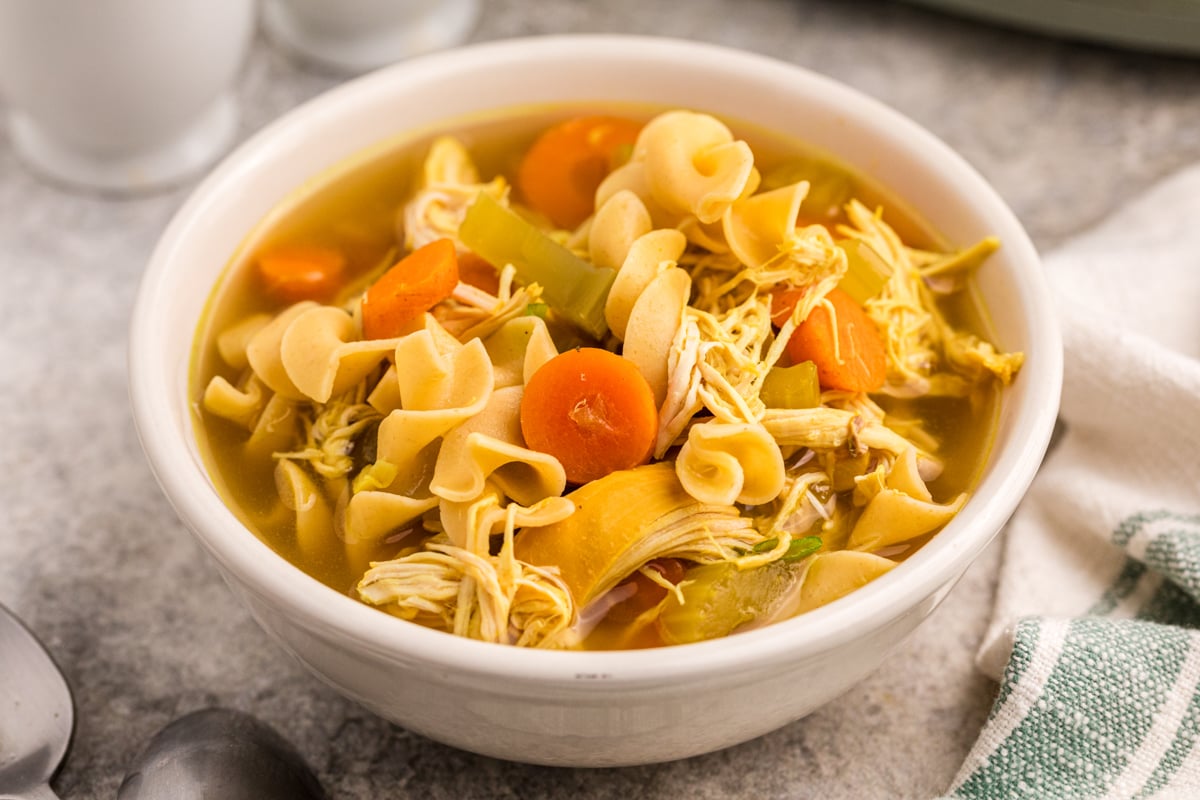 A serving of  slow cooker curried chicken noodle soup in a white bowl.