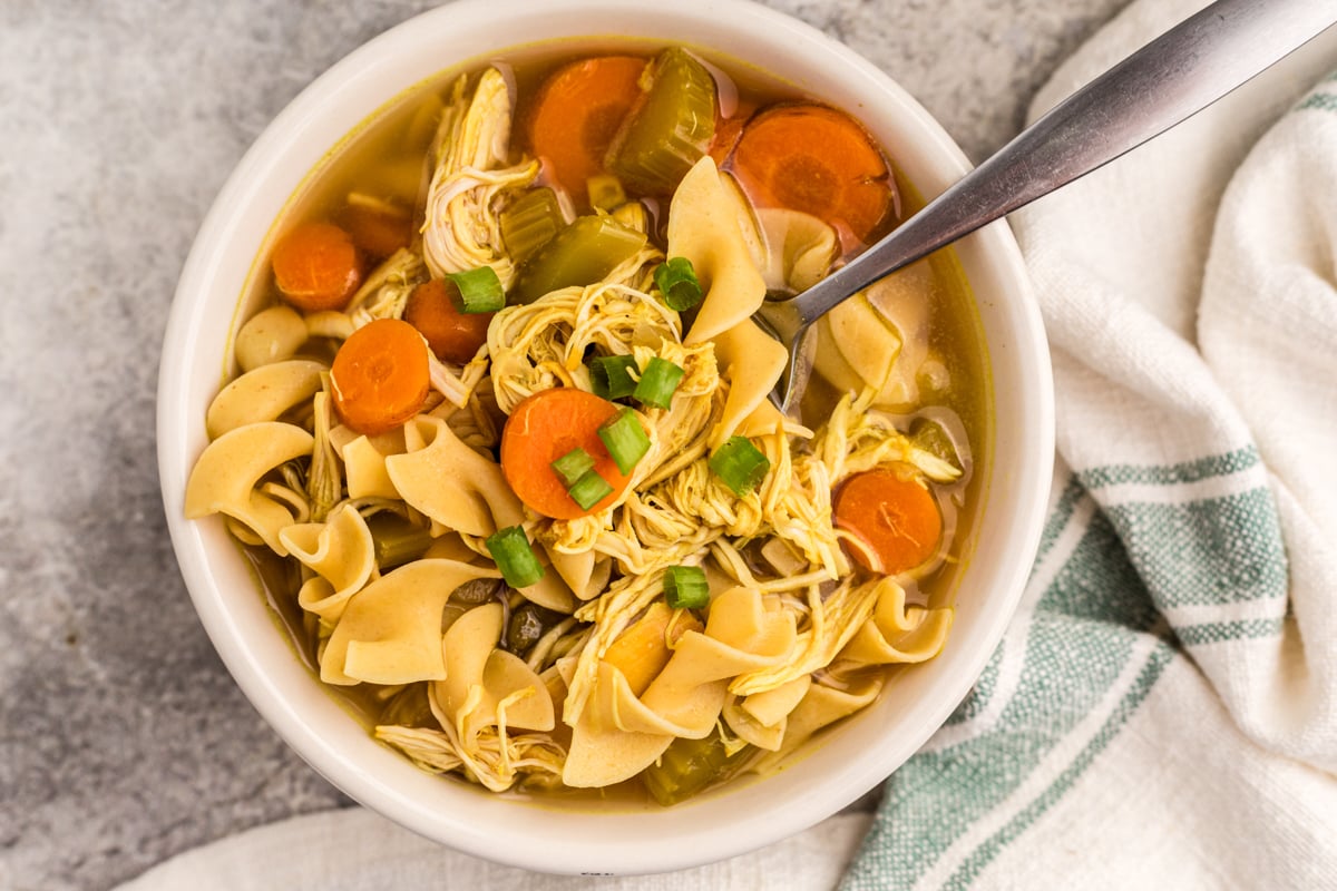 Slow cooker curried chicken noodle soup in a bowl with a spoon.