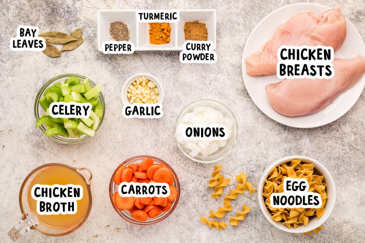 Ingredients for slow cooker curried chicken noodle soup on a table.