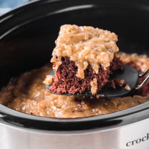 A spatula with a slice of German chocolate cake taken out of a slow cooker.