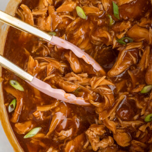 Slow cooker huli huli chicken with tongs ready to take some.
