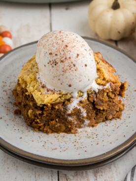 A slice of slow cooker pumpkin cobbler with a scoop of ice cream on top.