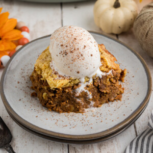 A slice of slow cooker pumpkin cobbler with a scoop of ice cream on top.