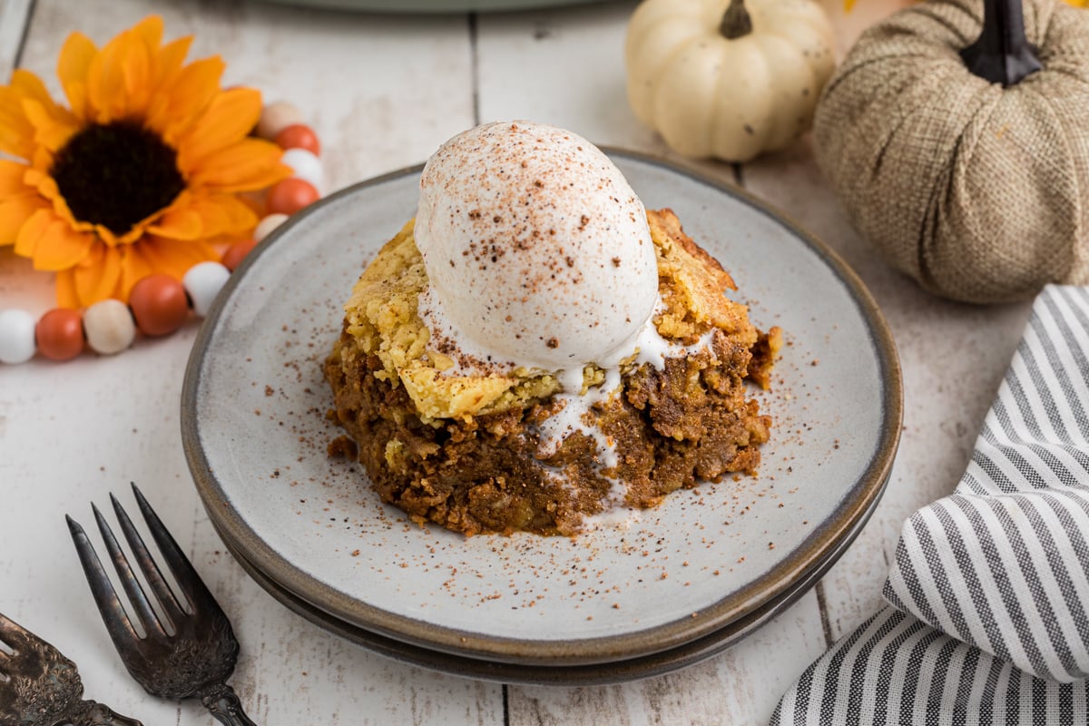 A slice of slow cooker pumpkin cobbler with a scoop of ice cream on top.