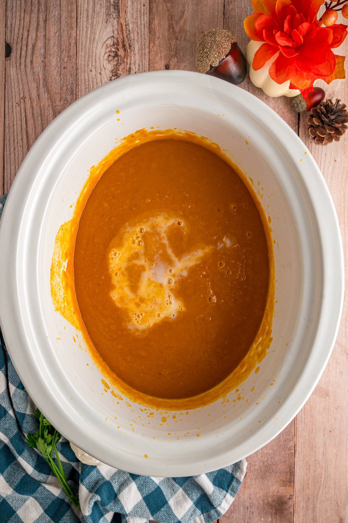 Coconut milk added to pumpkin soup in a slow cooker.