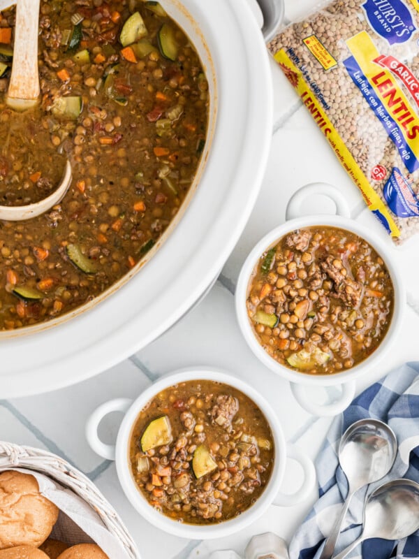 crockpot with sausage and lentil soup and bowls filled too.