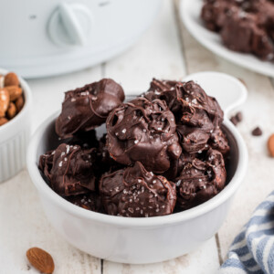 Slow cooker sea salt chocolate almond clusters in a white bowl.
