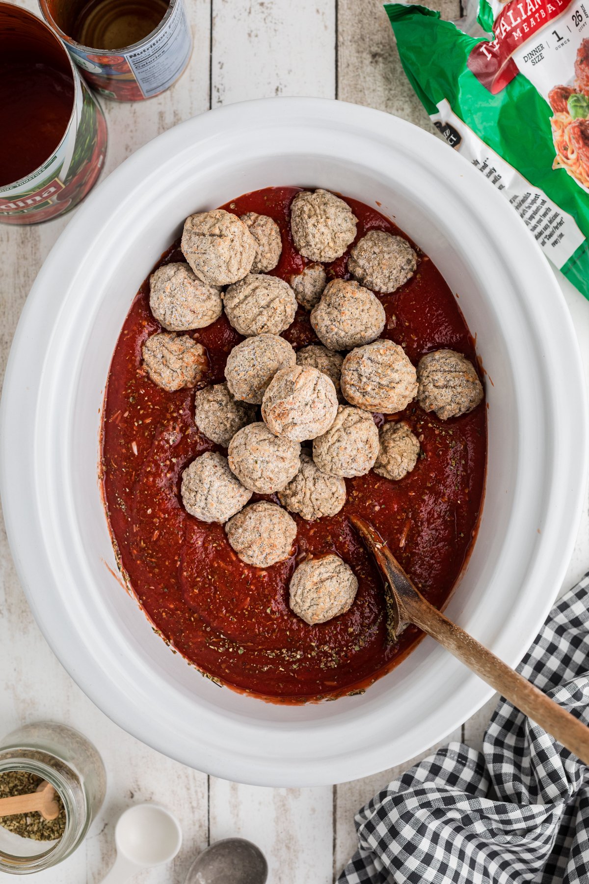 Frozen meatballs added to sauce in a slow cooker.