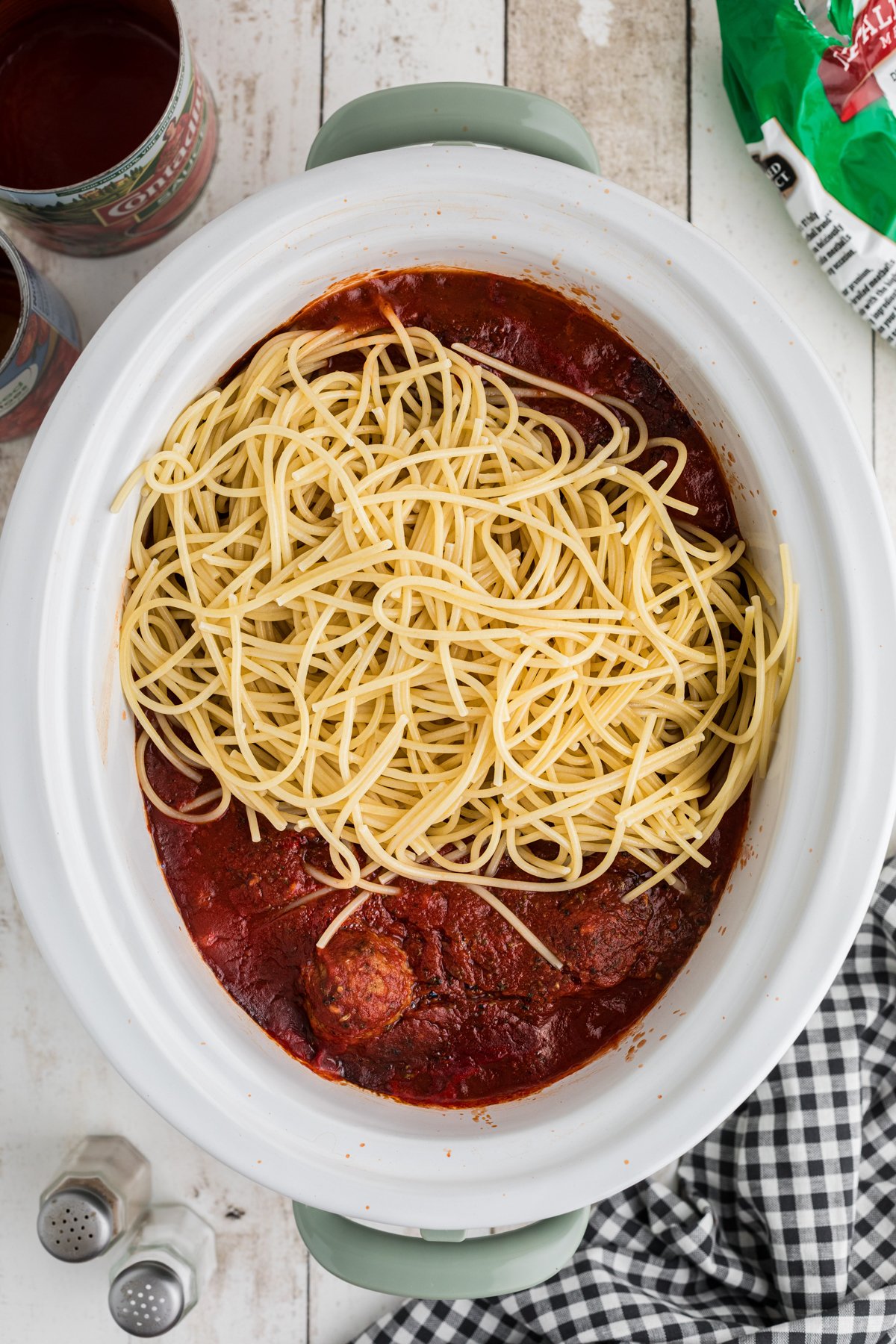 Cooked spaghetti added to sauce and meatballs in a slow cooker.