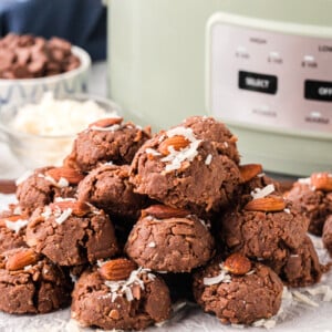 A pile of slow cooker almond joys in front of a crockpot.