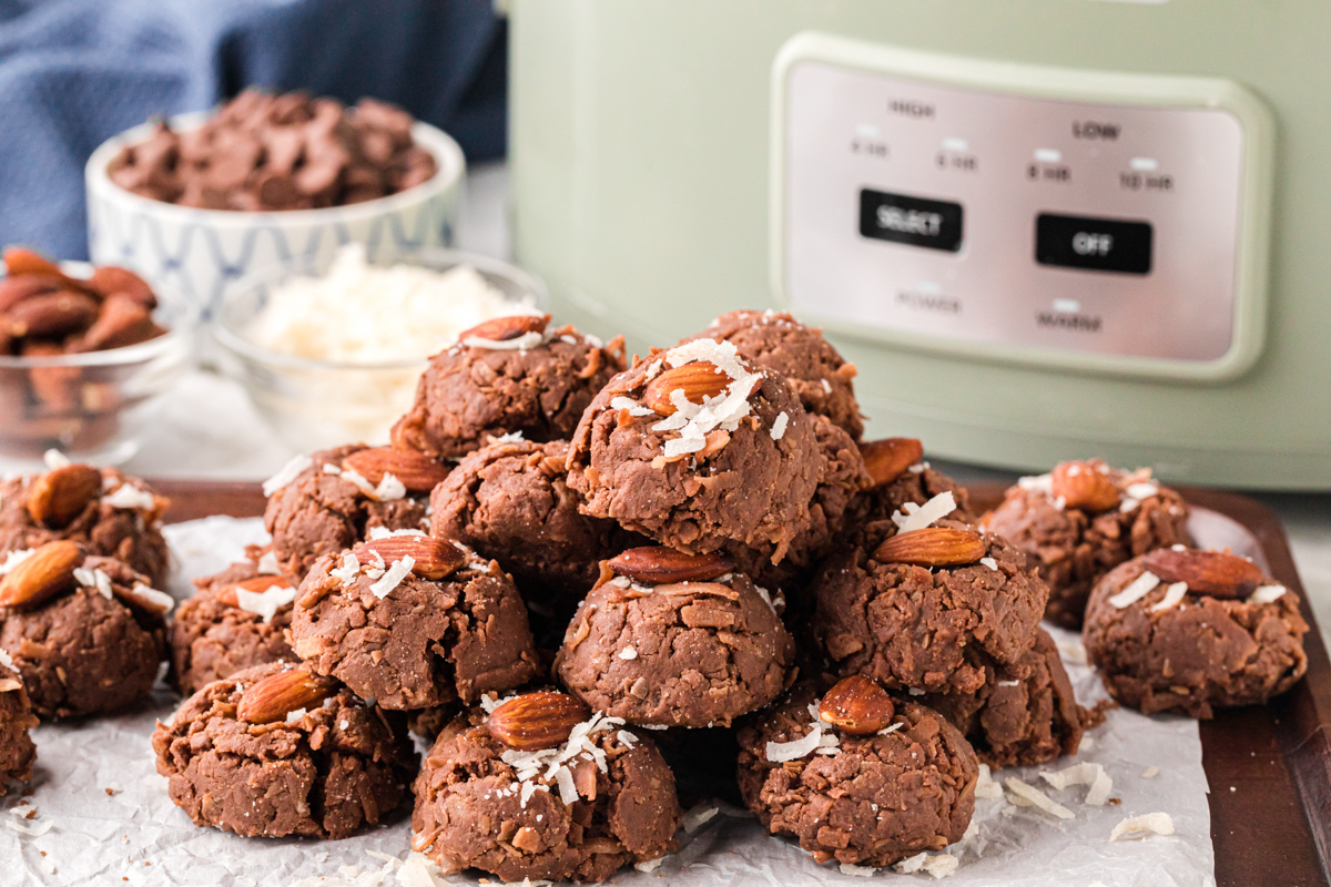 A pile of slow cooker almond joys in front of a crockpot.
