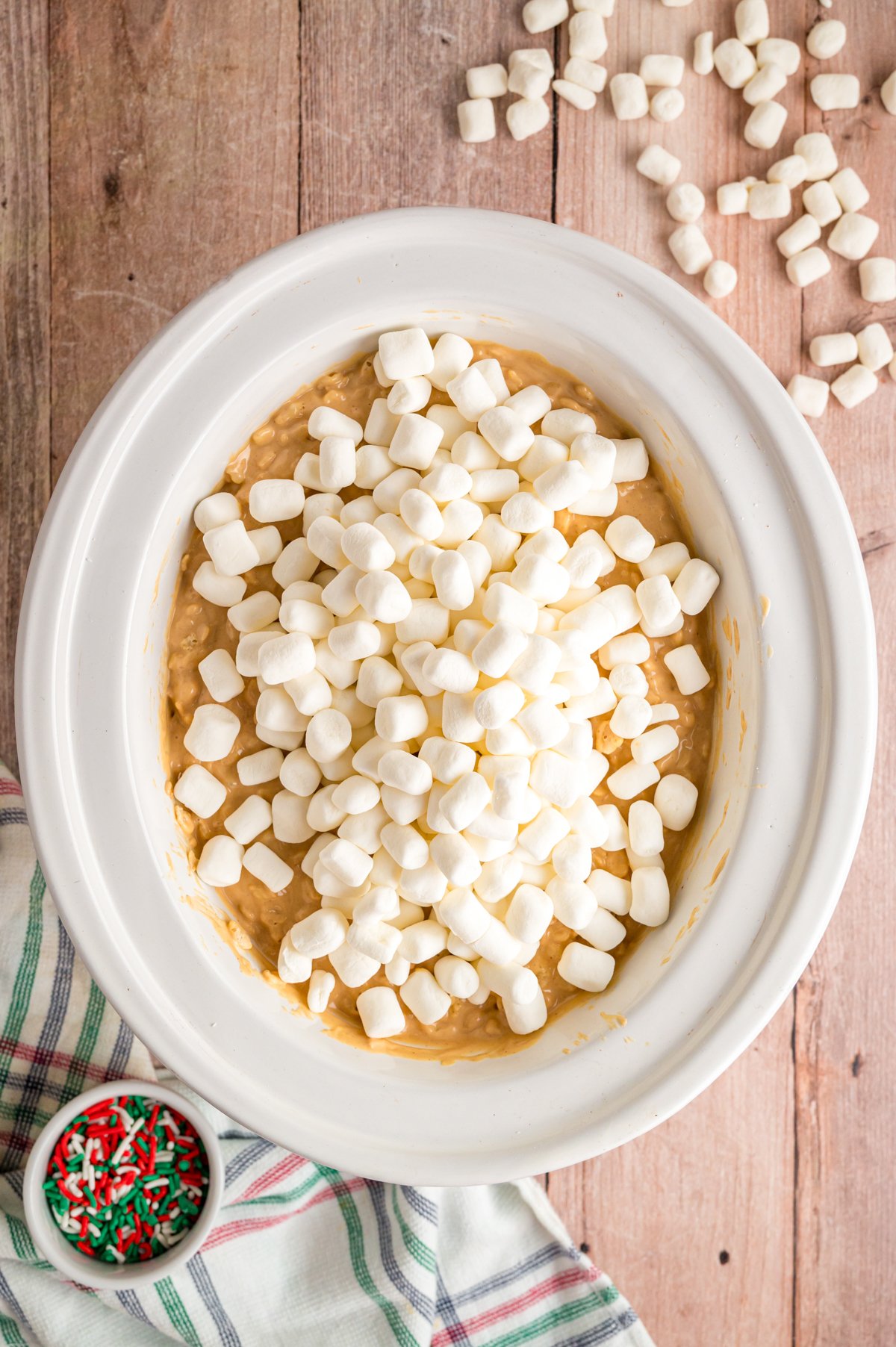 Mini marshmallows added to a mixture of melted almond bark and peanut butter and crispy rice cereal in a crockpot.