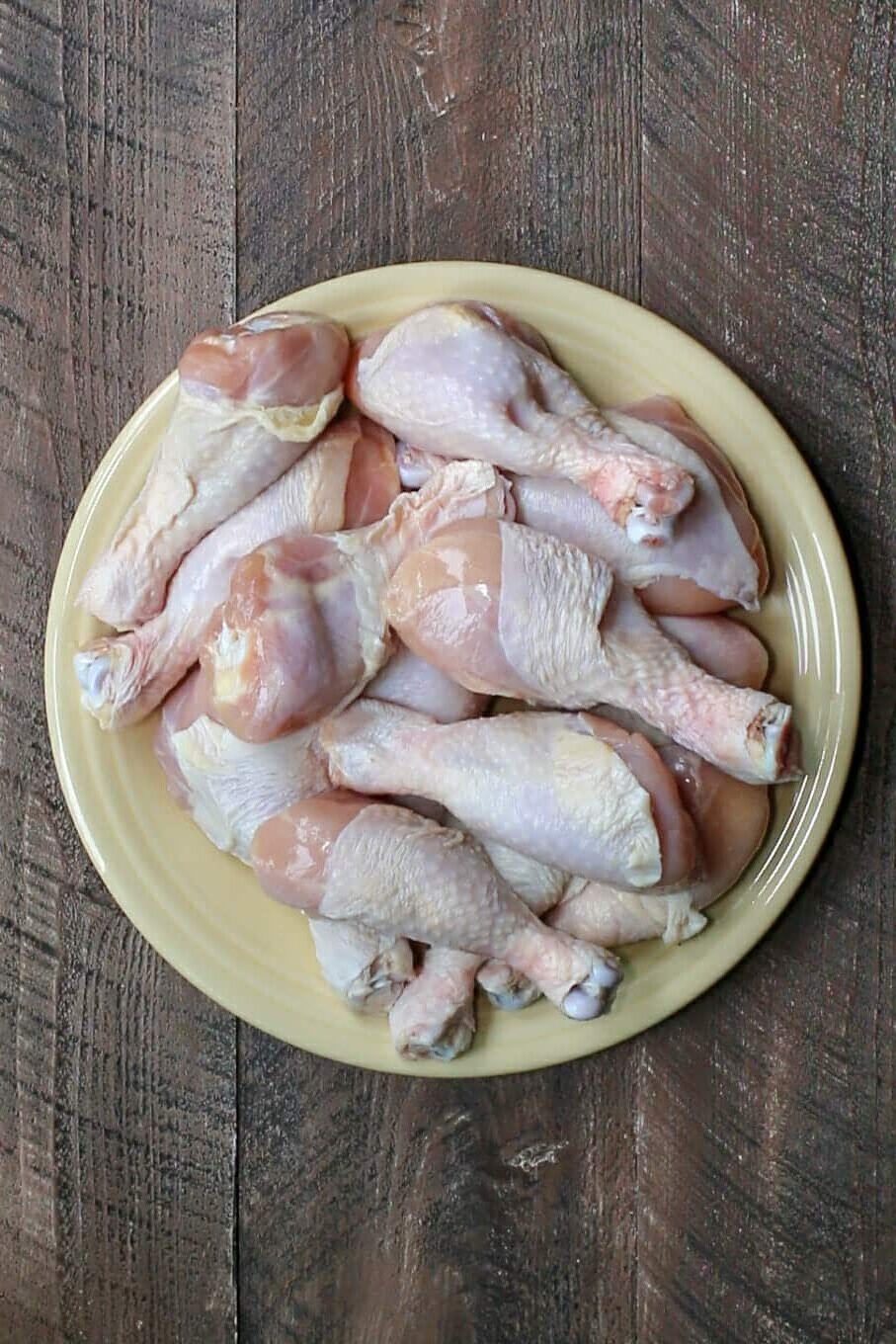 raw drumsticks on a yellow plate