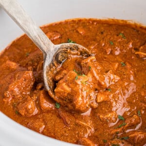 A spoon scooping out some slow cooker chicken curry.