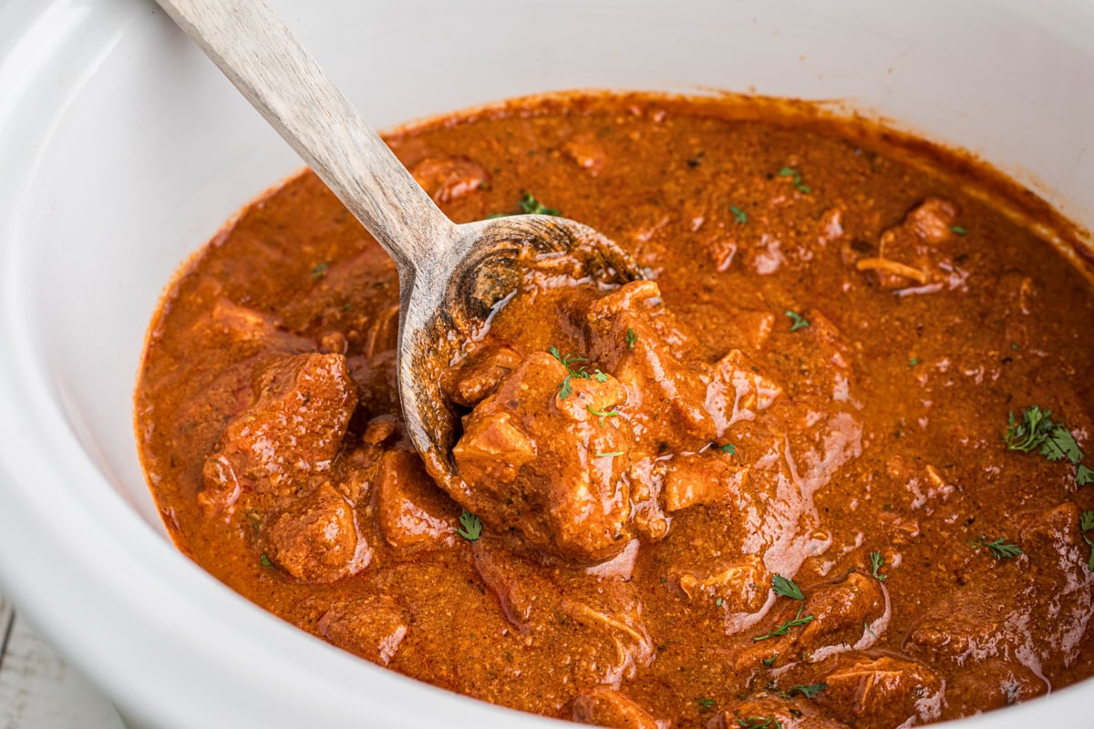 A spoon scooping out some slow cooker chicken curry.