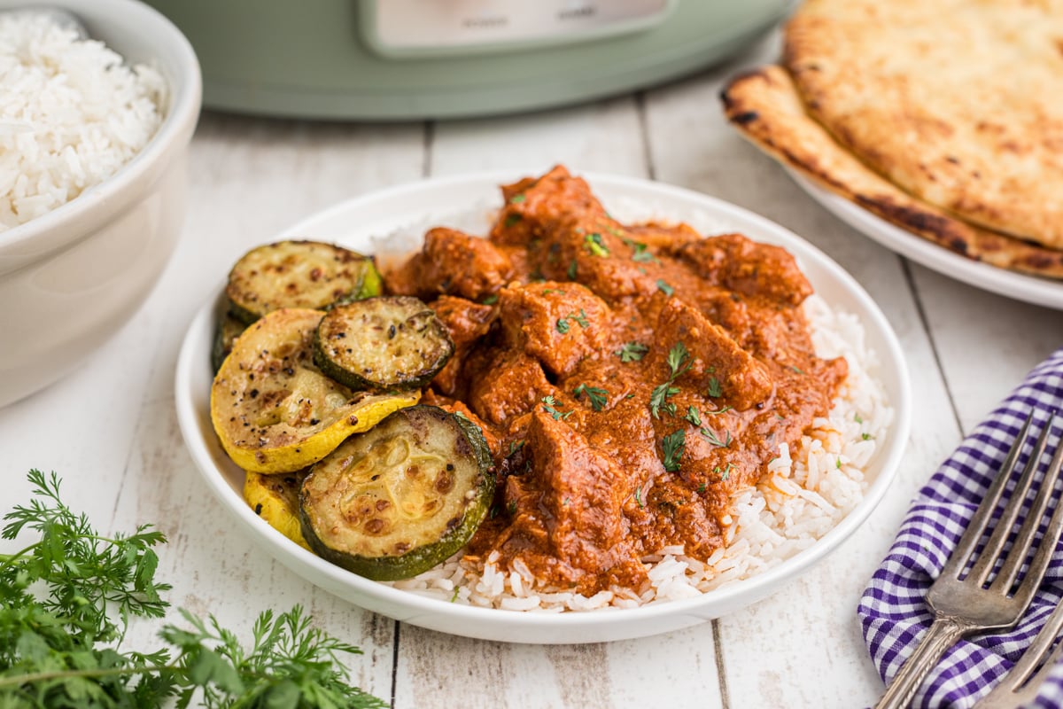 Slow cooker chicken curry with rice and veggies on a plate.