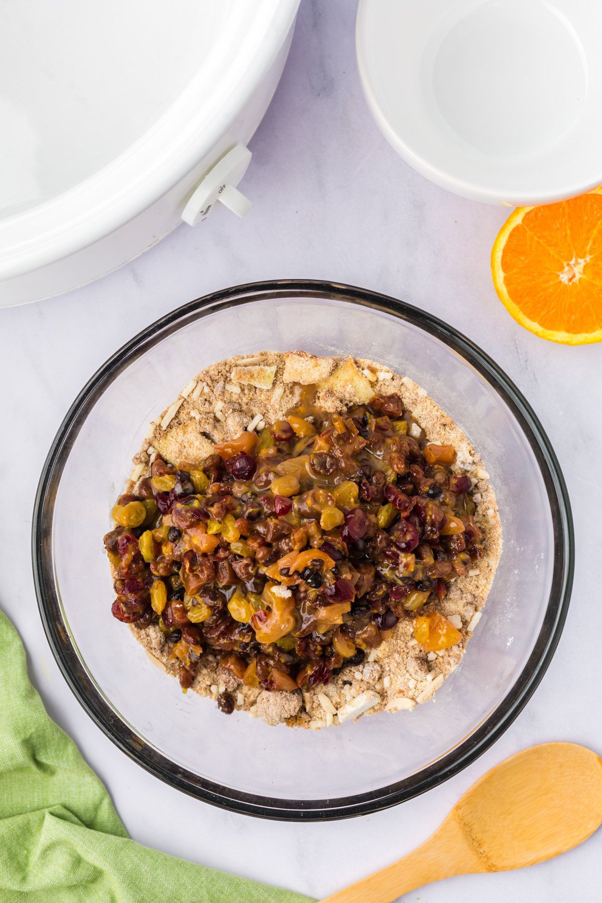 Fruit mixture added to dry ingredient mixture in a glass bowl.