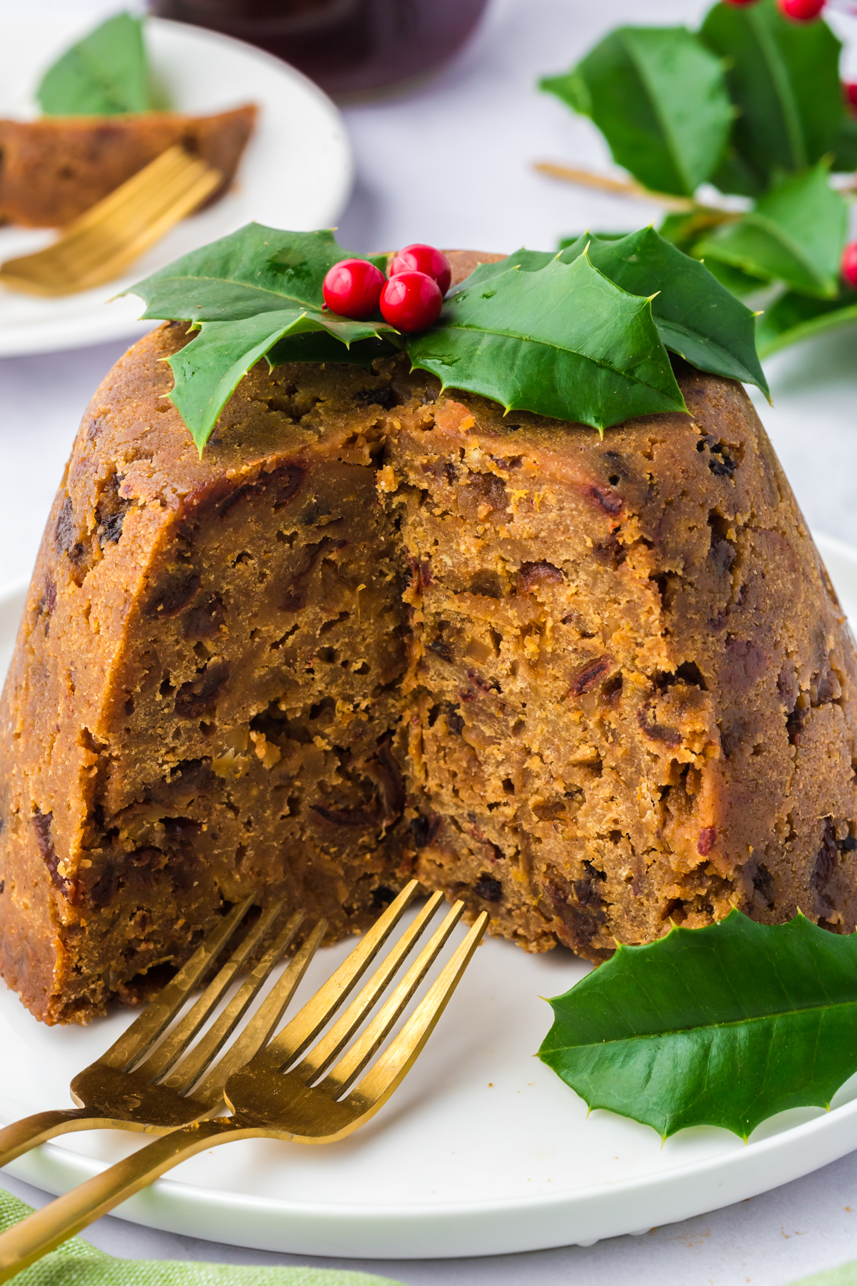 Slow cooker figgy pudding on a plate with a slice cut out of the front.
