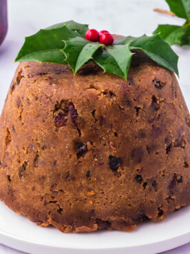 Slow cooker figgy pudding on a white plate with festive garnish.
