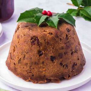 Slow cooker figgy pudding on a white plate with festive garnish.