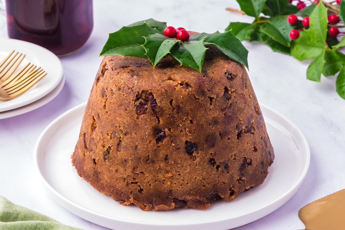 Slow cooker figgy pudding on a white plate with festive garnish.