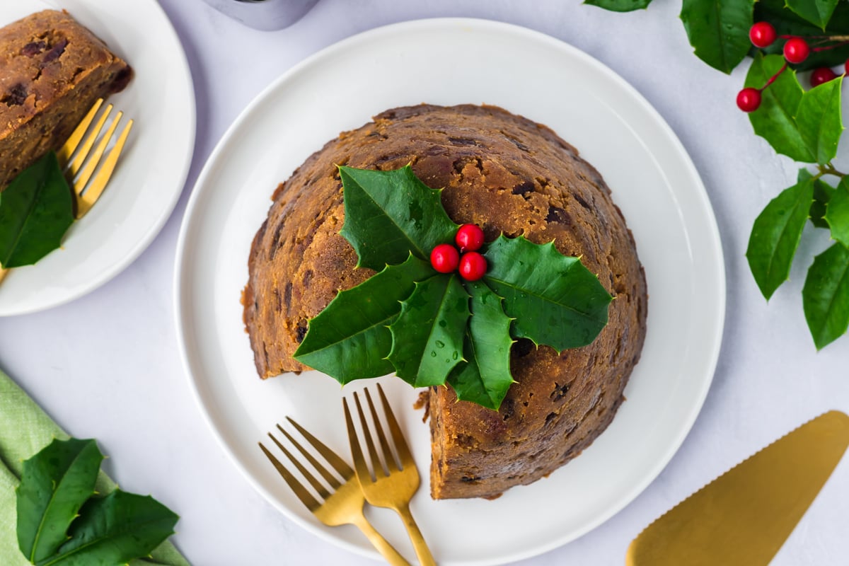 Slow cooker figgy pudding on a plate with a piece missing and two forks.