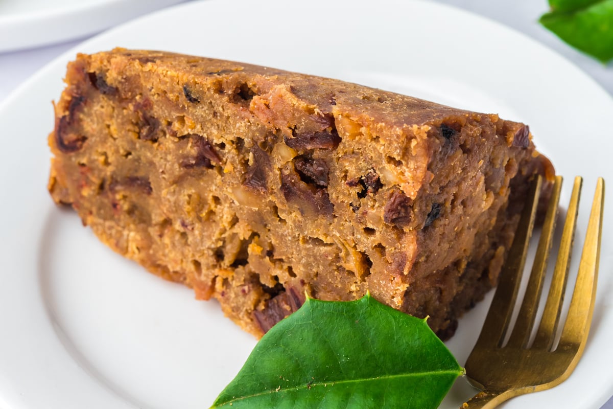 Close-up of a slice of slow cooker figgy pudding on a plate with a fork.