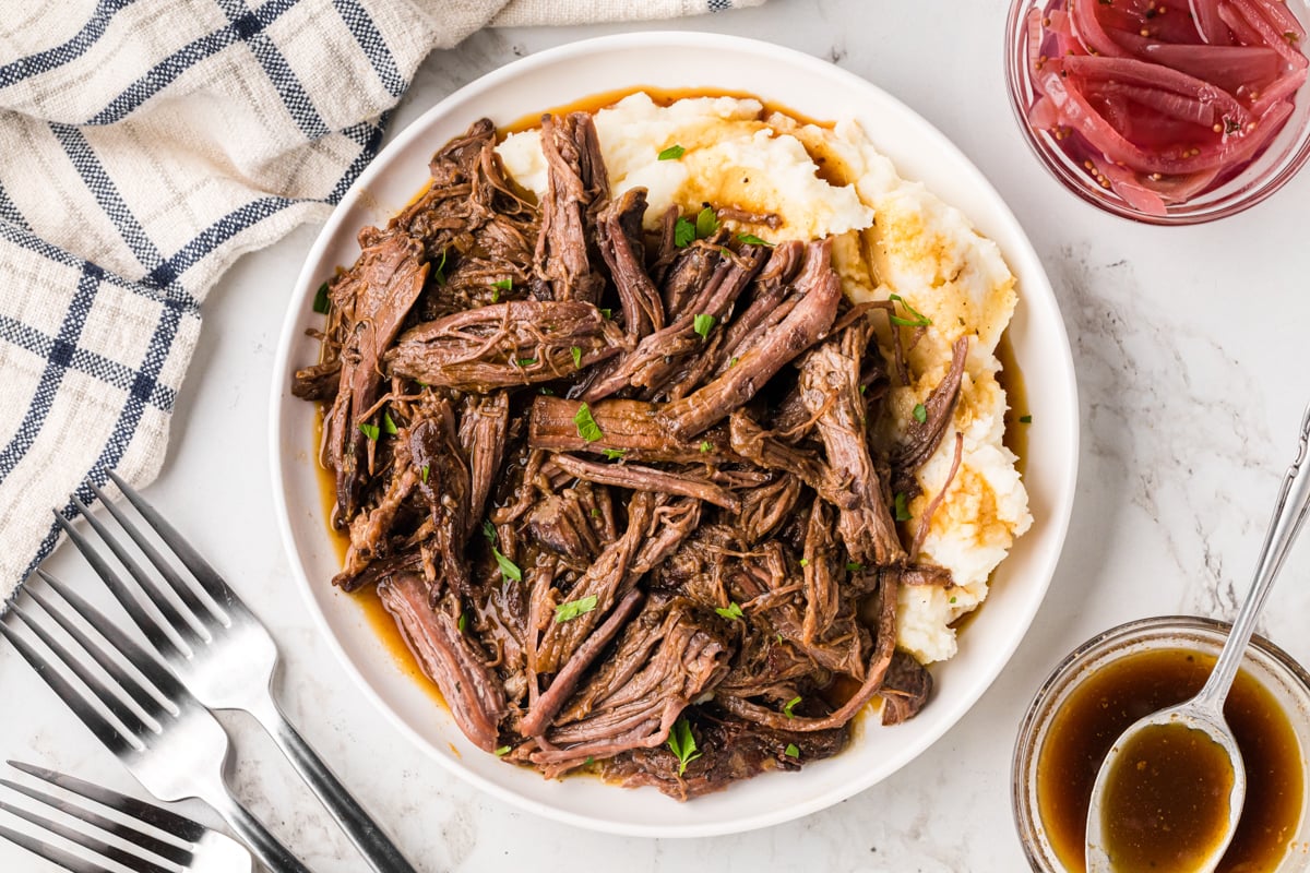 Slow cooker pot roast on a plate with mashed potatoes.