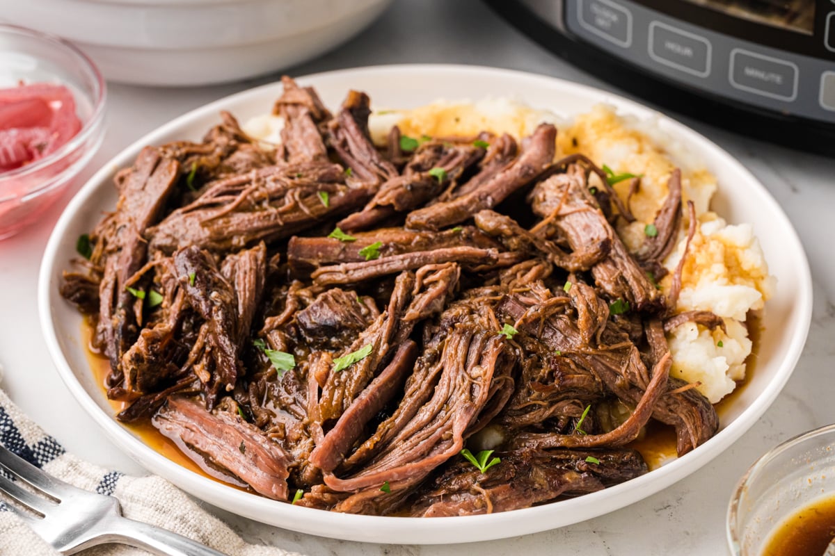 A close-up of a serving of slow cooker pot roast on a plate.