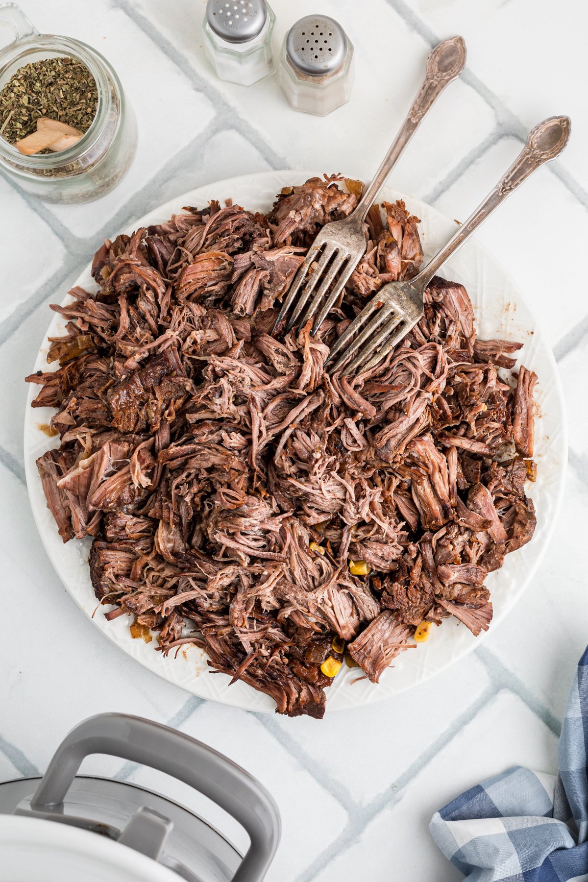 Shredded beef on a plate with two forks.