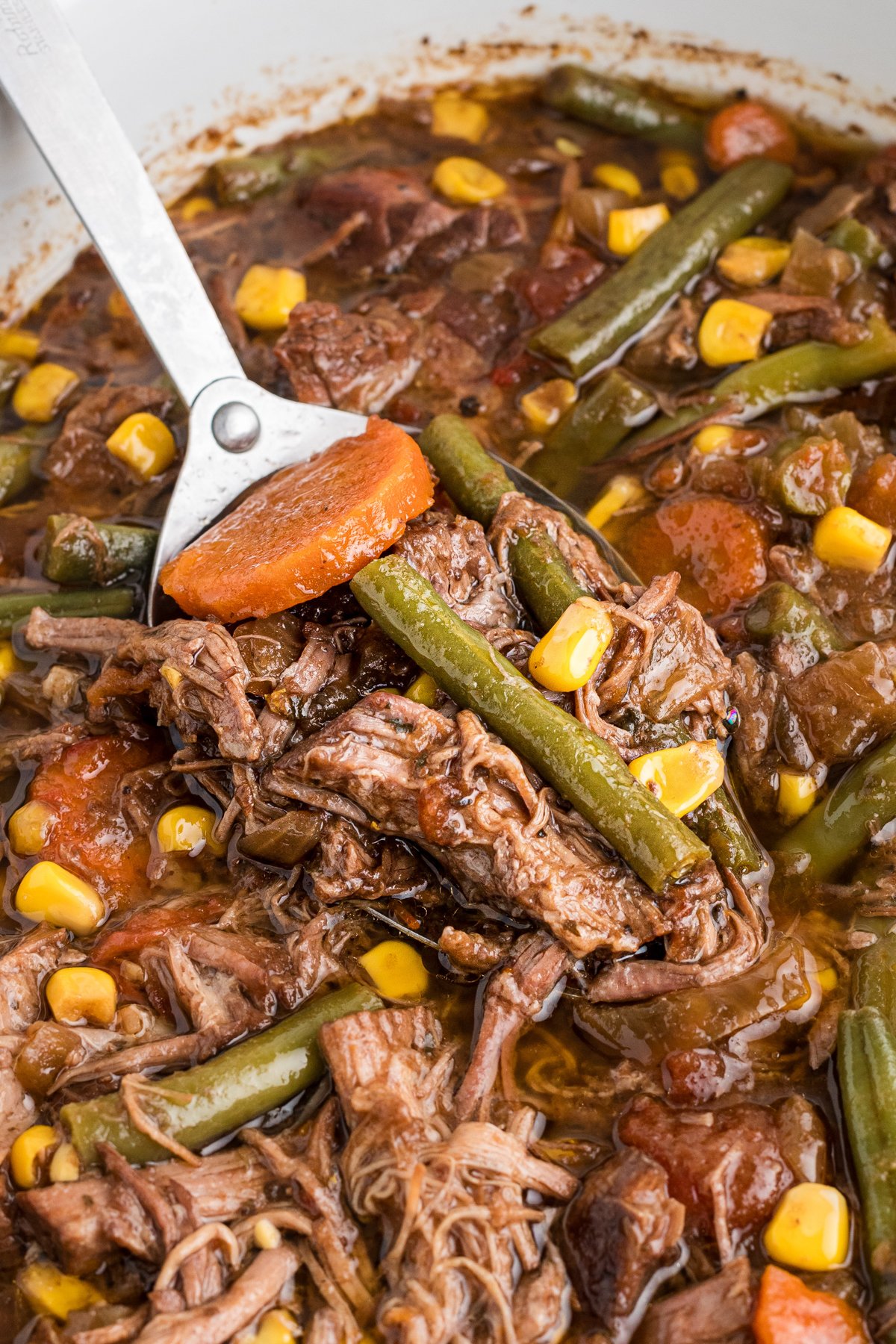 Slow cooker shredded beef dinner with a spoon in it.