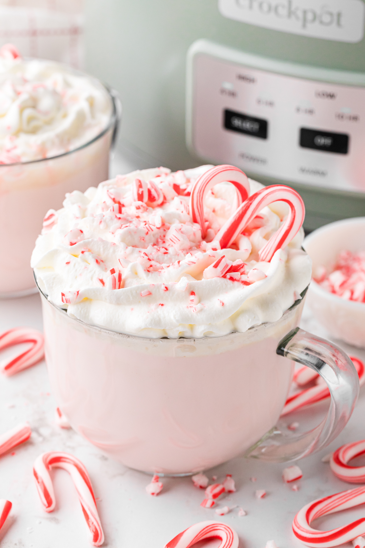 Slow cooker candy cane hot chocolate in a mug with candy canes around it.