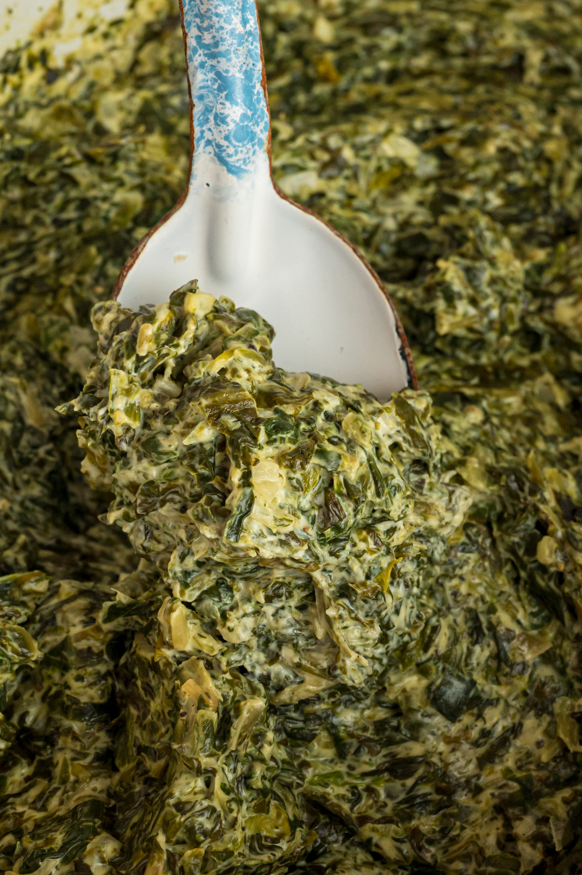 A spoon scooping out some slow cooker creamed spinach.
