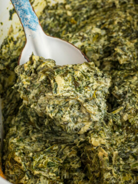 Slow cooker creamed spinach with a spoon in it.